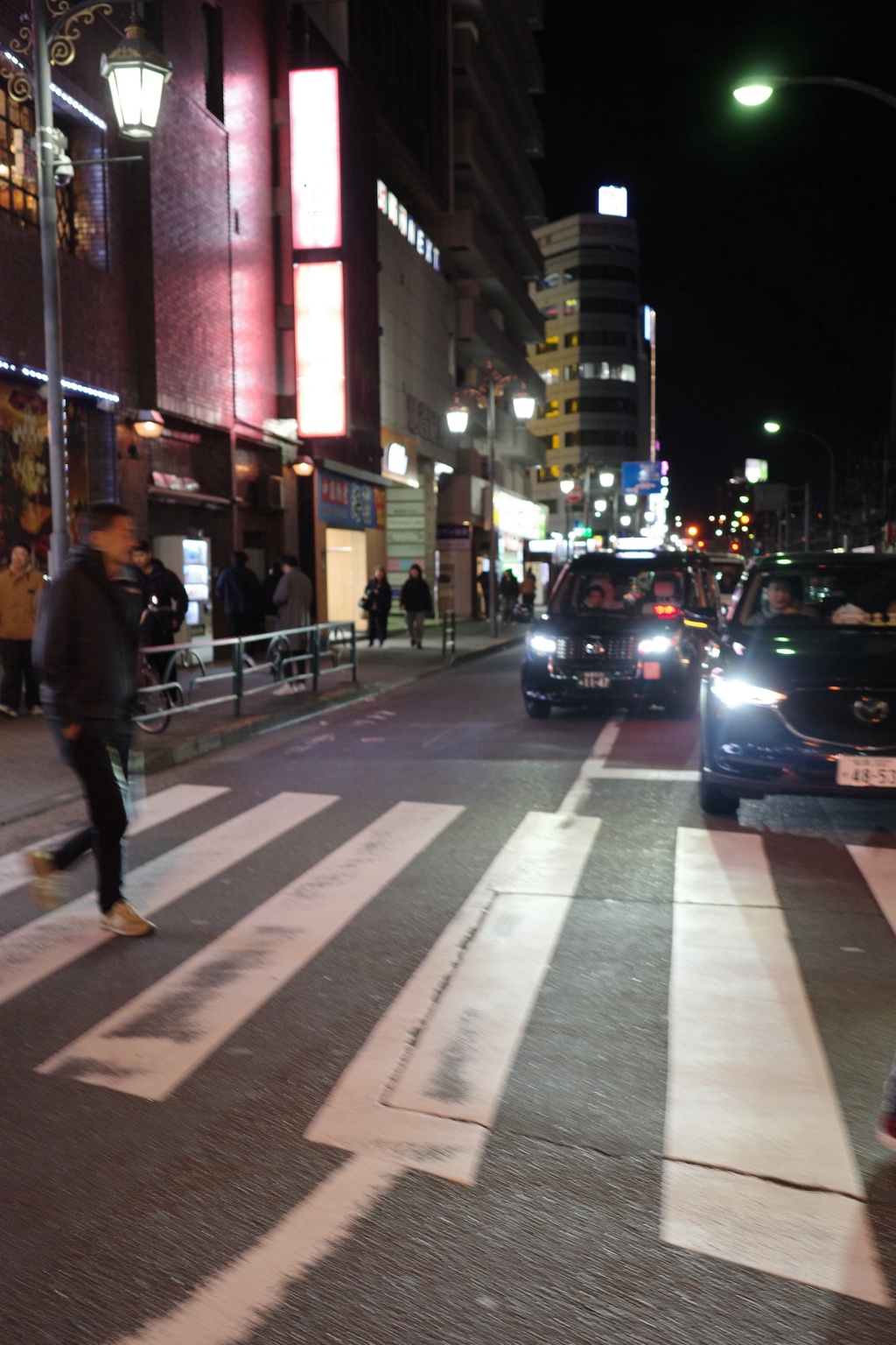 夜間城市街道、行人與迎面車燈